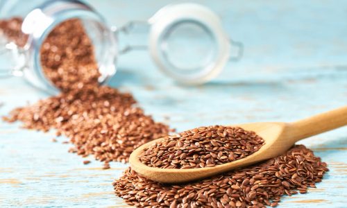 1 flax seeds are poured from glass jar into wooden spoon 1 1